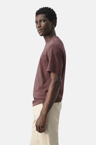 T-shirt marron à manches courtes de MANGO, porté avec un pantalon beige et une texture unie en vue de côté.