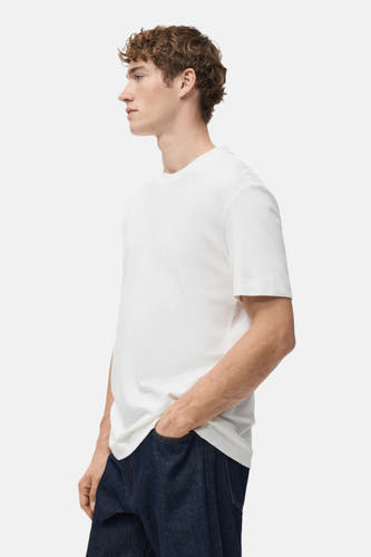 T-shirt blanc à manches courtes de MANGO, porté avec des jeans foncés, montré sur le côté.