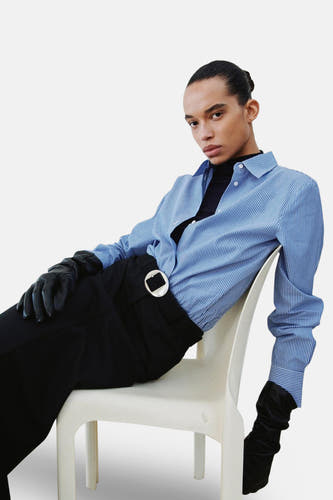 Chemise bleue rayée à manches longues de MANGO, vue de derrière, avec un pantalon noir.