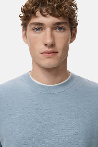 T-shirt bleu marine à col rond de MANGO, avec une fine texture et porté sur un t blanc.