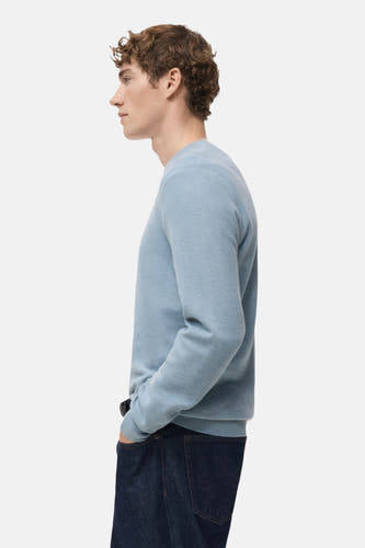 T-shirt bleu avec col rond de MANGO, porté en vue latérale avec des jeans foncés.