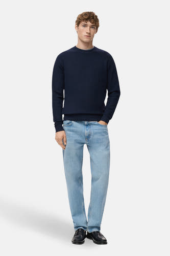 T-shirt bleu avec col rond de MANGO, porté avec des jeans bleus clairs et des loafers en cuir noirs.