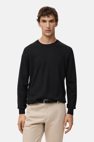 Pull noir avec col rond de MANGO, vu de derrière, associé à un pantalon beige.