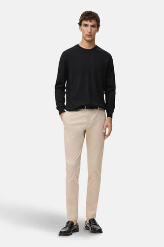 Pull noir avec col rond de MANGO, porté avec un pantalon beige et des chaussures en cuir noires.
