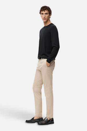 Pull noir avec col rond de MANGO, associé à des chinos beige et des loafers en cuir noir.