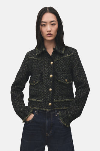 Blazer vert de MANGO, met een geweven textuur en gerafelde details, gedragen met een donkerblauwe jeans.