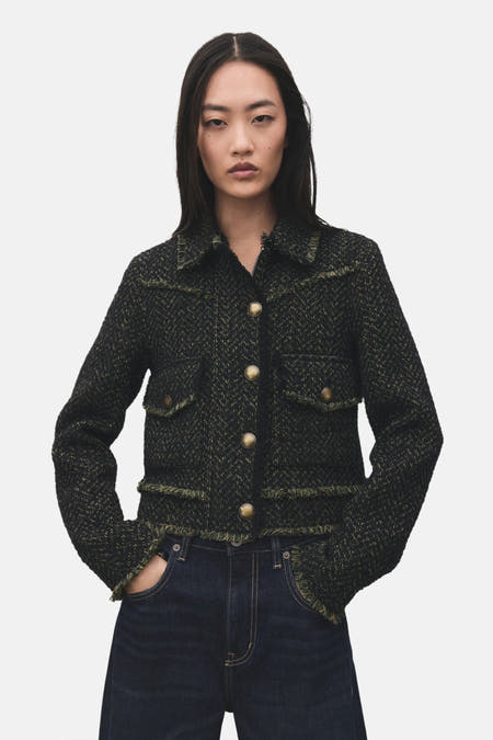 Blazer vert de MANGO, met een geweven textuur en gerafelde details, gedragen met een donkerblauwe jeans.