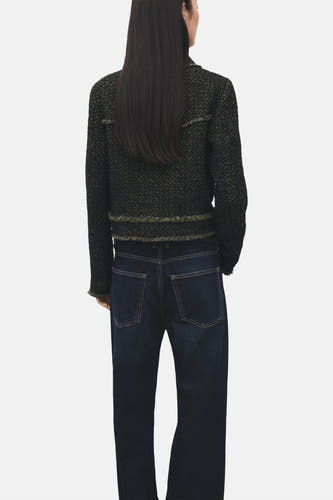Groene blazer van MANGO, met een geweven textuur en gerafelde details, gedragen met een donkerblauwe jeans.