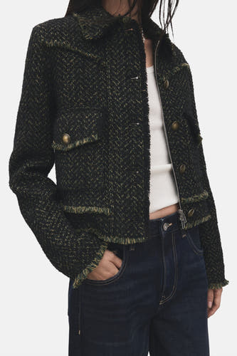 Blazer vert de MANGO avec une texture tweed-like et des détails froncés, associé à un haut blanc et un jeans foncé.
