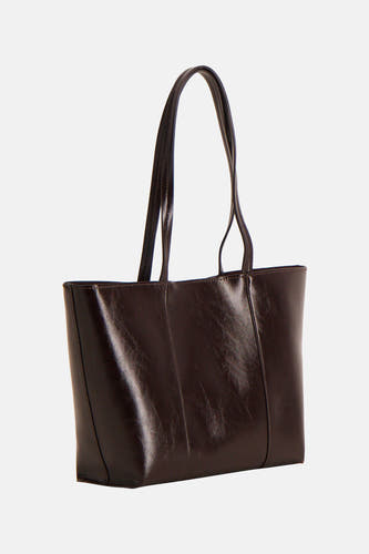 Sac à main marron de MANGO, avec une texture lisse et de longues anses, sur un fond uni.