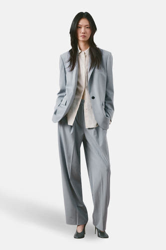 Blazer bleu de MANGO, porté sur une chemise rayée et assorti à un pantalon assorti.