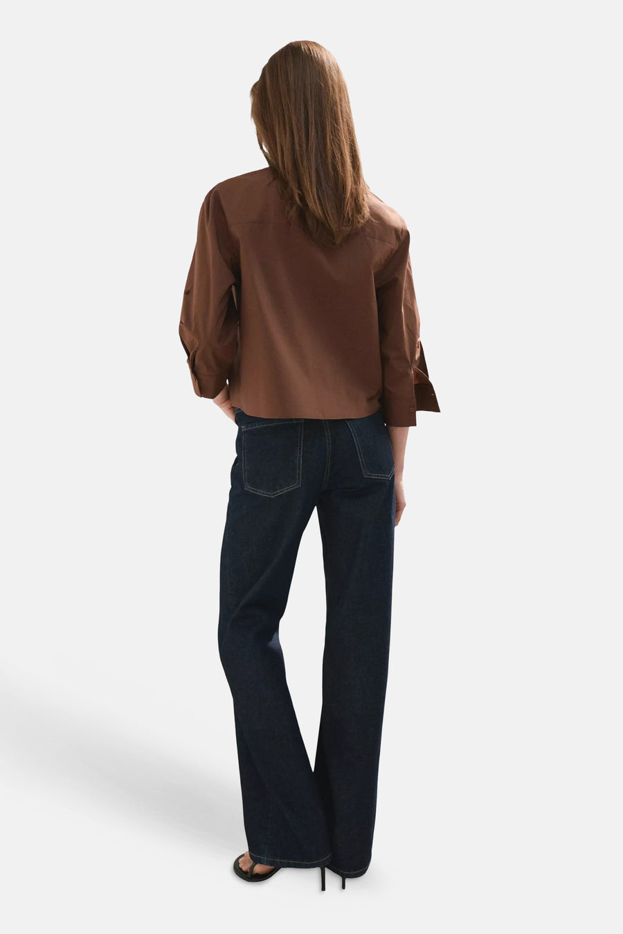 Bruin hemd van MANGO met opgerolde lange mouwen, van achteren gezien op model met donkere jeans en teenslippers.