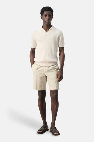 Polo écru de MANGO, à manches courtes et à la texture côtelée, combinée avec un short beige et des sandales en cuir.