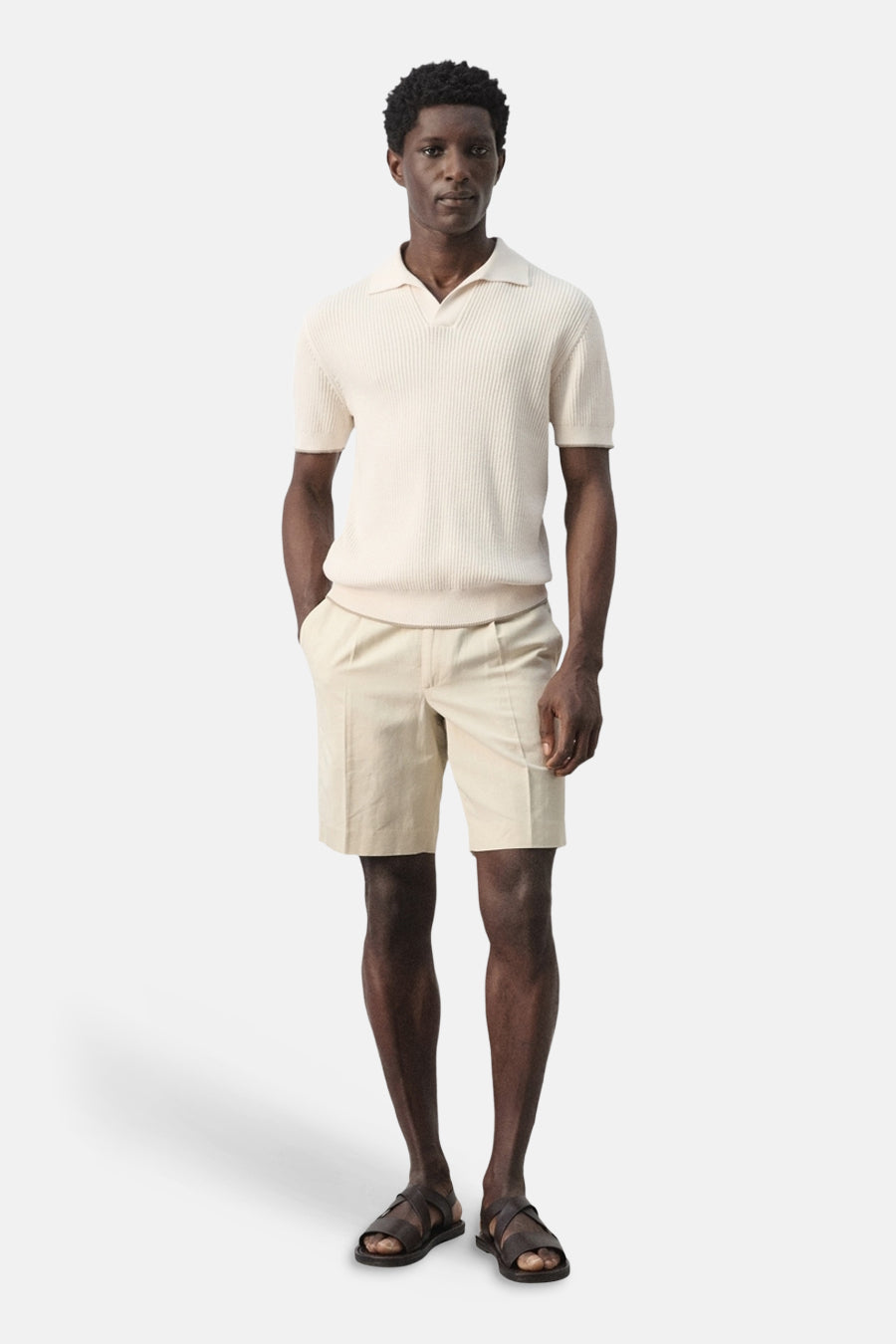 Polo écru de MANGO, à manches courtes et à la texture côtelée, combinée avec un short beige et des sandales en cuir.