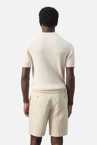 Ecru polo van MANGO, geribd gebreid met korte mouwen en effen lichtbeige shorts.