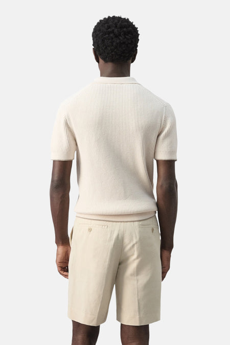 Ecru polo van MANGO, geribd gebreid met korte mouwen en effen lichtbeige shorts.