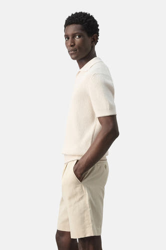 Polo écru de MANGO, côtelée et à manches courtes, portée avec un short beige.