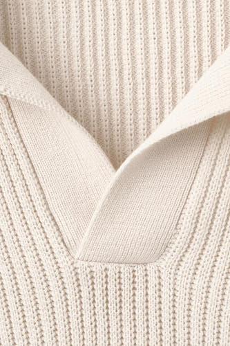 Polo écru de MANGO avec une texture côtelée et un col en V ouvert.