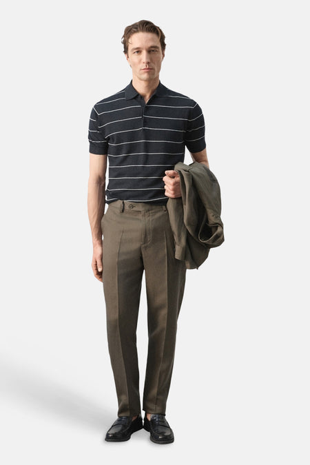 Polo noire de MANGO, avec des rayures horizontales blanches, combinée avec un pantalon kaki et des chaussures noires.