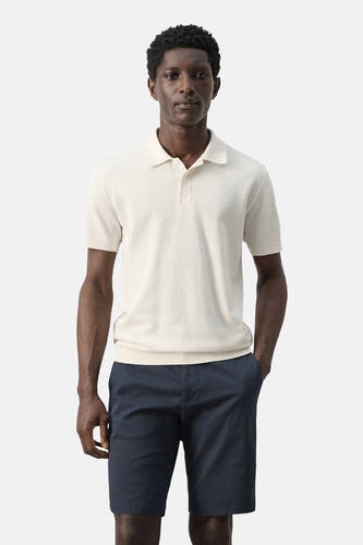 Polo écru de MANGO, dos, à manches courtes et short bleu marine.