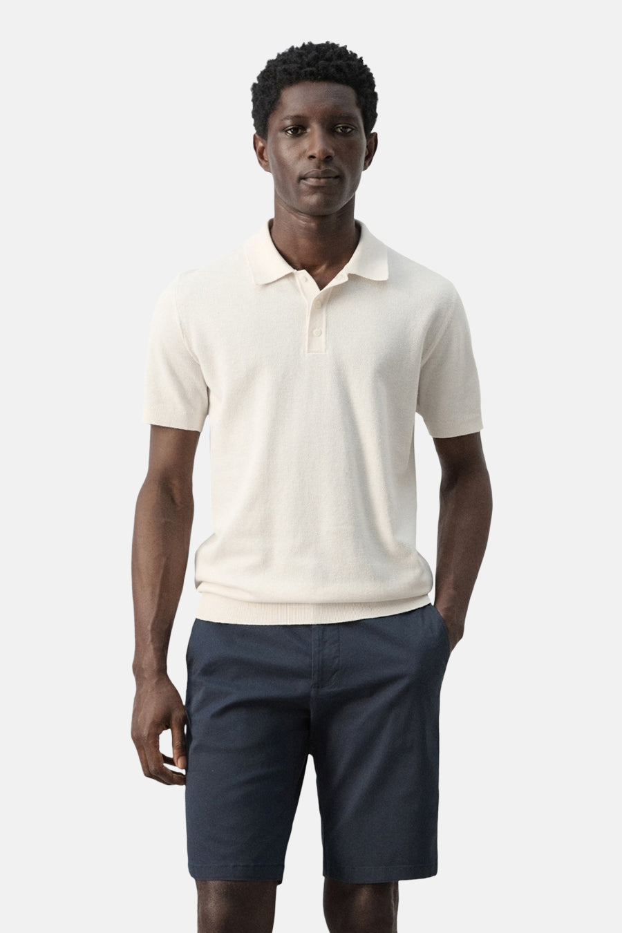 Polo écru de MANGO, dos, à manches courtes et short bleu marine.