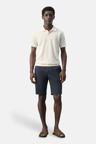 Polo écru de MANGO, combinée avec un short bleu marine et des sandales marron.