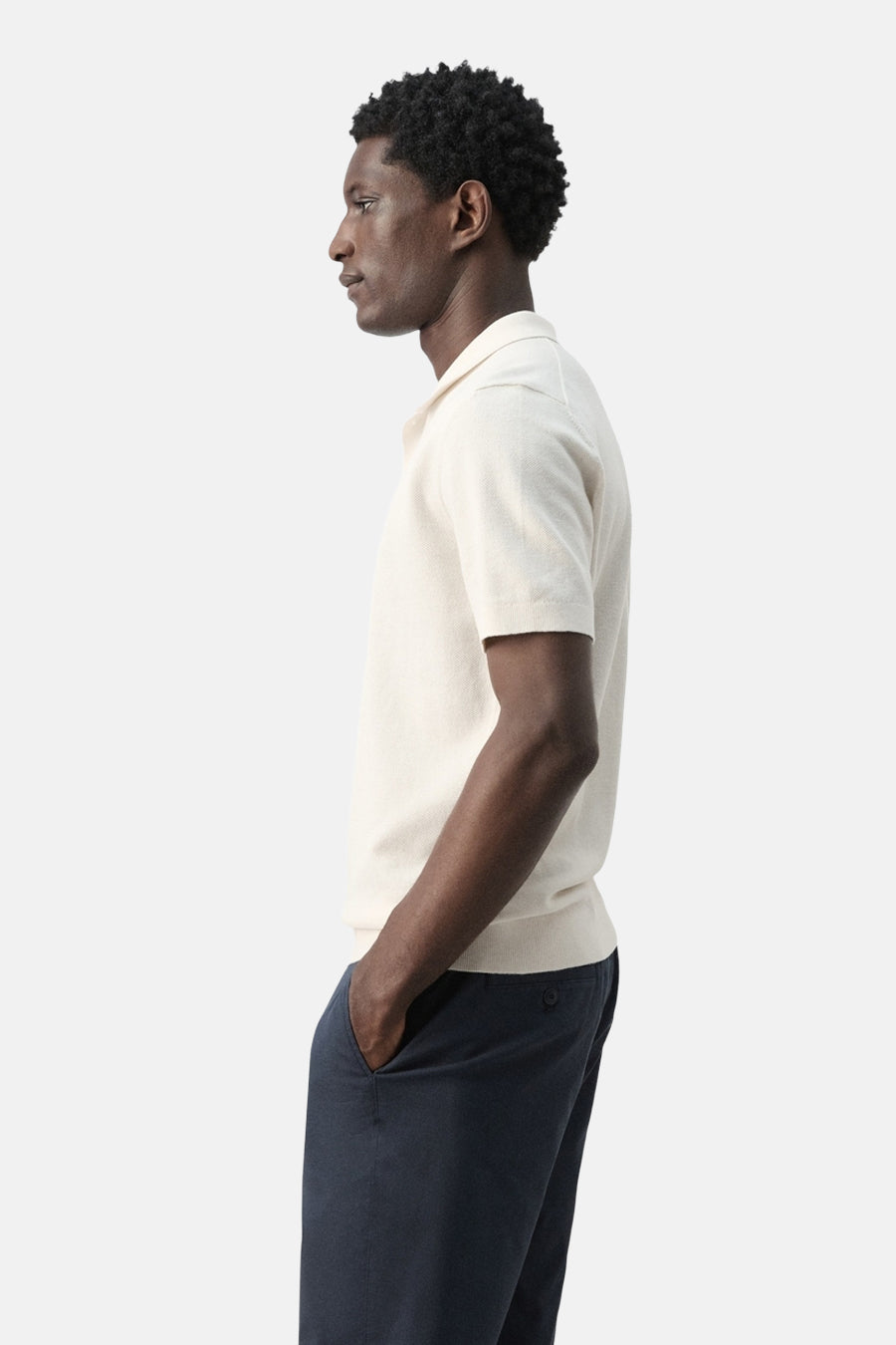 Polo écru de MANGO, vue de côté, à manches courtes et pantalon bleu foncé.