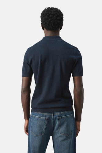 Blauwe polo van MANGO, achterkant gezien, gecombineerd met een jeansbroek.