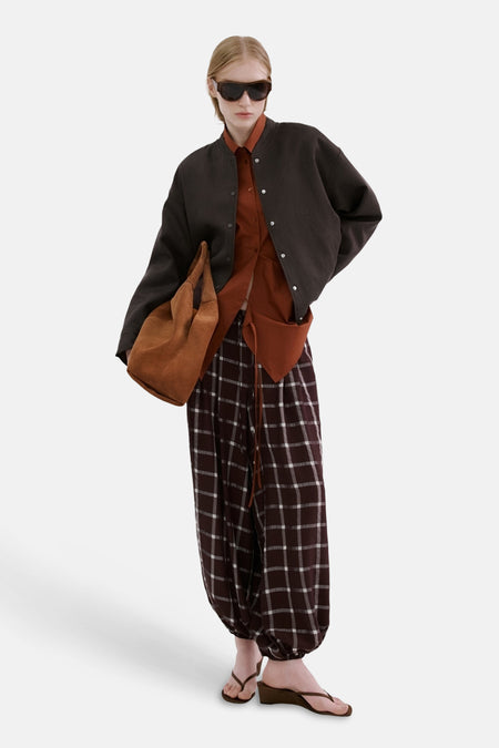 Blazer marron de MANGO, à manches longues et fermeture boutonnée, combinée avec une chemise marron et un pantalon à carreaux.