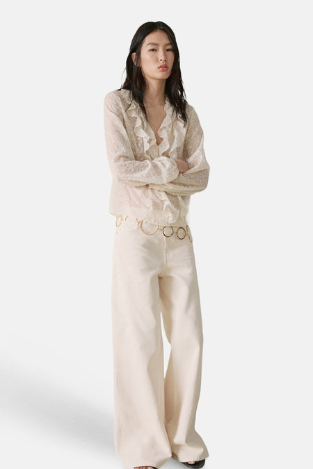 Chemisier écru à manches longues de MANGO avec volants et motif à pois subtil, combiné avec un pantalon large et une ceinture dorée.