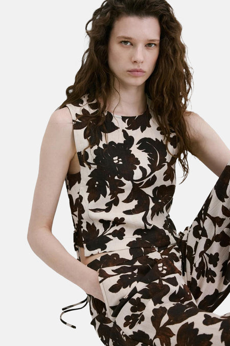 Chemisier court sans manches de couleur écru à motif floral marron foncé de MANGO, porté avec un pantalon assorti, vu de côté/arrière.