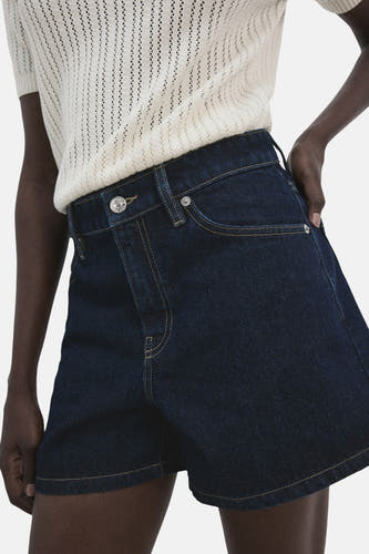 Bermuda en denim bleu marine de MANGO, avec poches arrière et combiné avec un haut en maille.