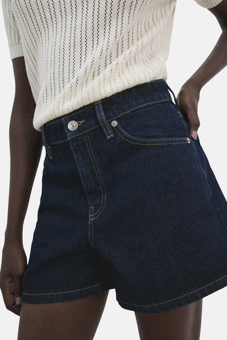 Bermuda en denim bleu marine de MANGO, avec poches arrière et combiné avec un haut en maille.