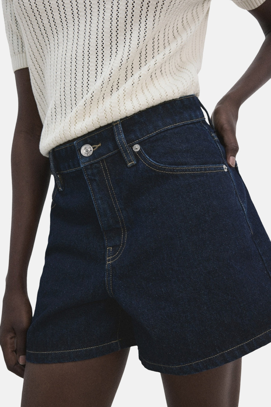 Bermuda en denim bleu marine de MANGO, avec poches arrière et combiné avec un haut en maille.