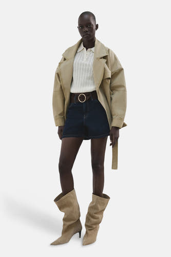 Short en jean bleu marine de MANGO, avec une ceinture marron et une grande boucle ronde, combiné avec des bottes.