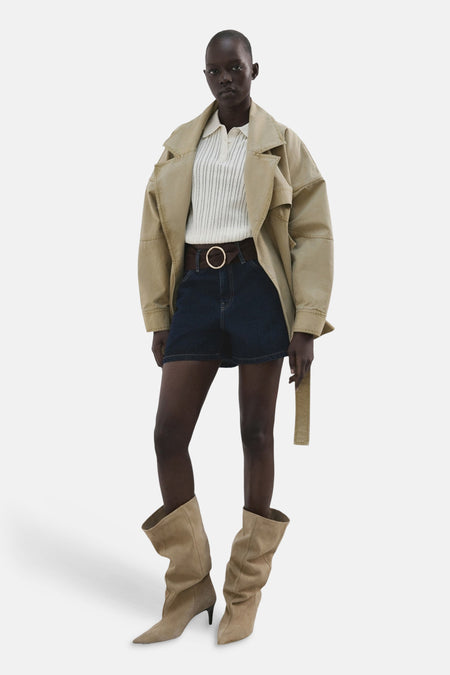 Short en jean bleu marine de MANGO, avec une ceinture marron et une grande boucle ronde, combiné avec des bottes.