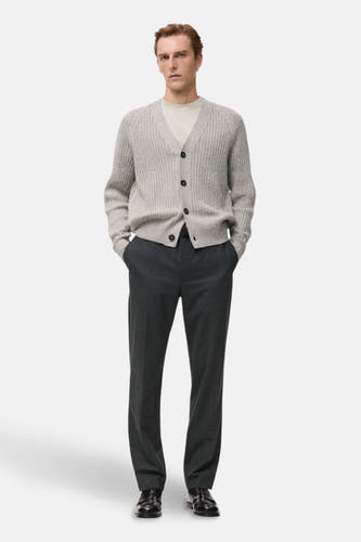 Pantalon gris de MANGO, associé à une chemise claire grise avec des boutons et des chaussures noires.