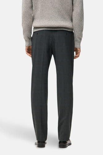 Grijze broek van MANGO, gezien vanaf de achterkant, gecombineerd met een gebreide trui en zwarte schoenen.