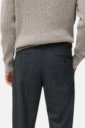 Pantalon gris de MANGO, avec des poches à boutons sur l'arrière, associé à une chemise repassée.