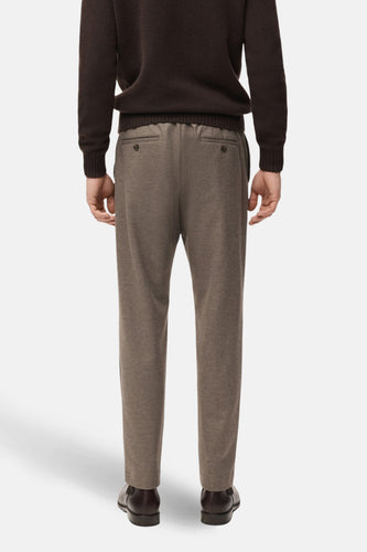 Achterkant van een man met een bruine trui en bruine broek.