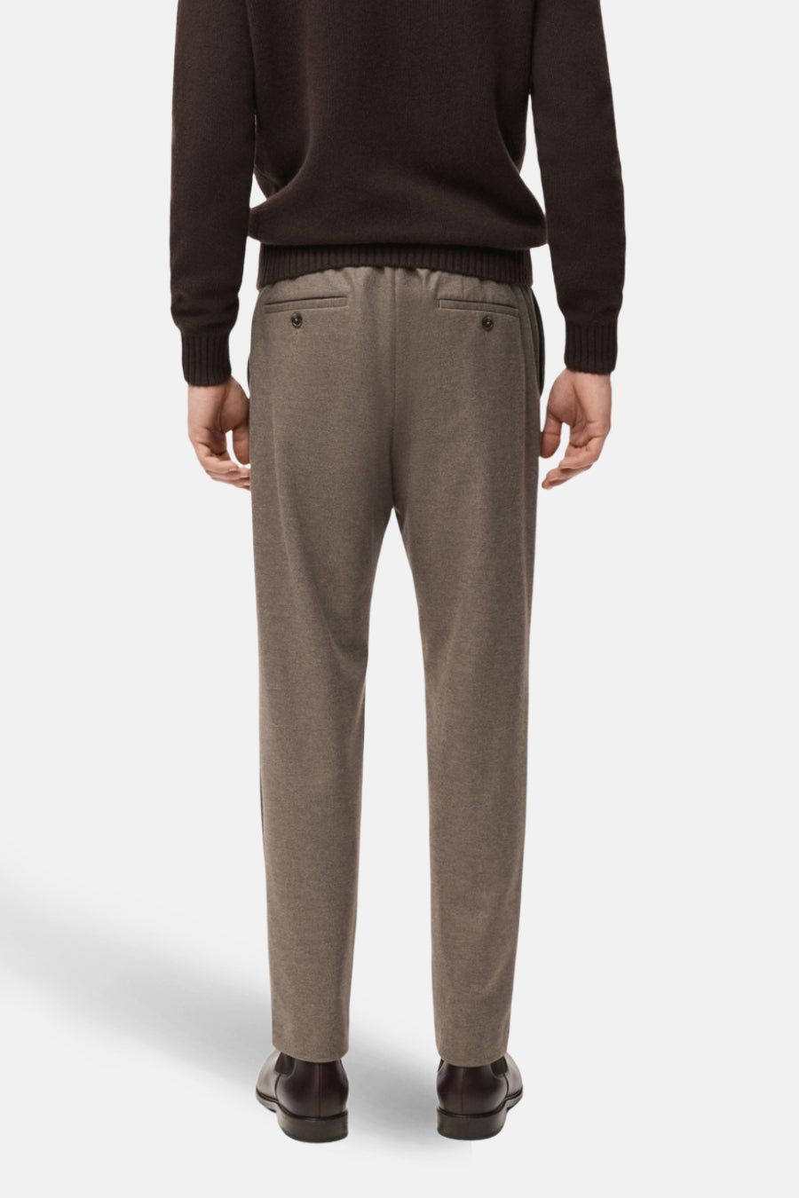 Achterkant van een man met een bruine trui en bruine broek.