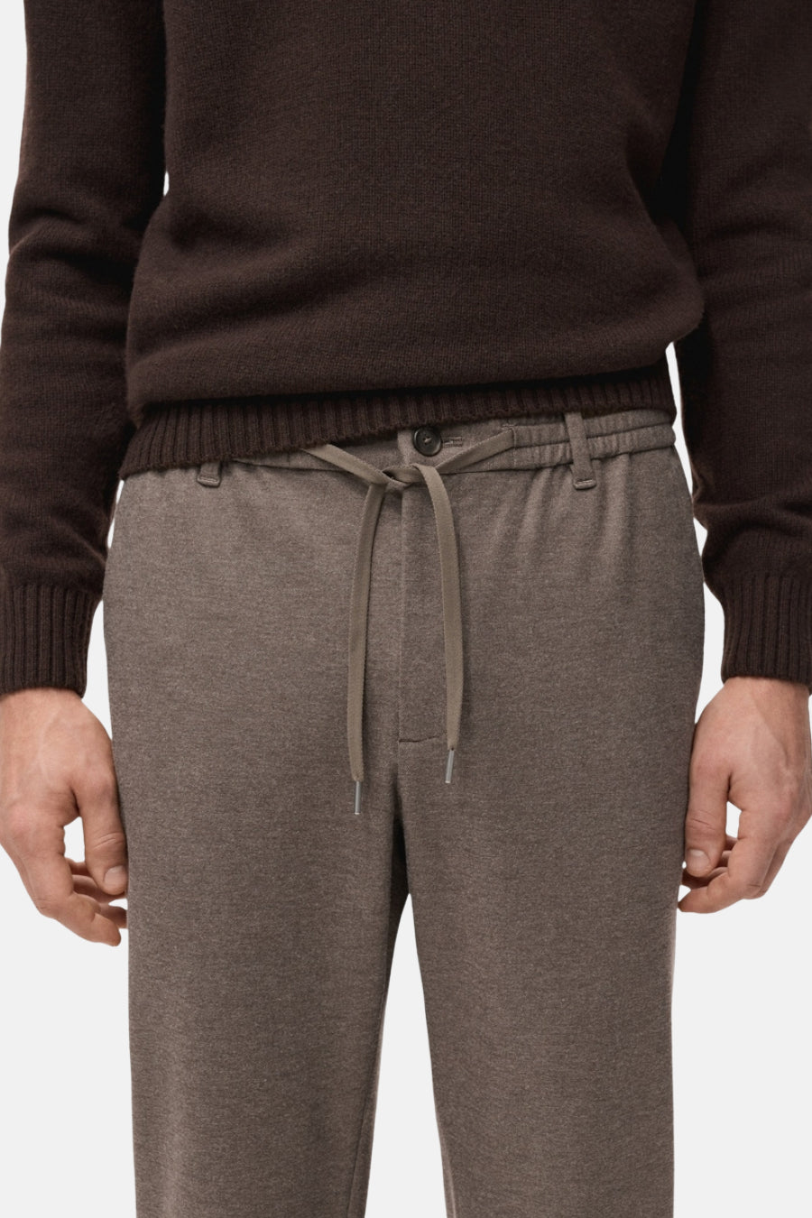 Bruine trui en grijze joggingbroek.