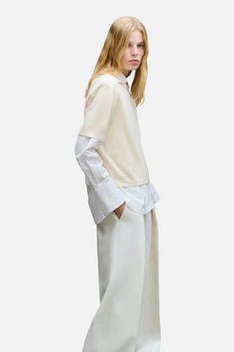 Veste écru avec col rond de MANGO, portée avec un chemisier blanc et un pantalon crème.