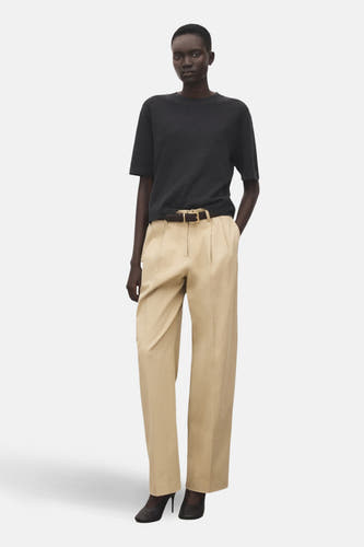 Sweat-shirt gris avec col rond de MANGO, porté avec un pantalon beige à ceinture et des chaussures foncées.