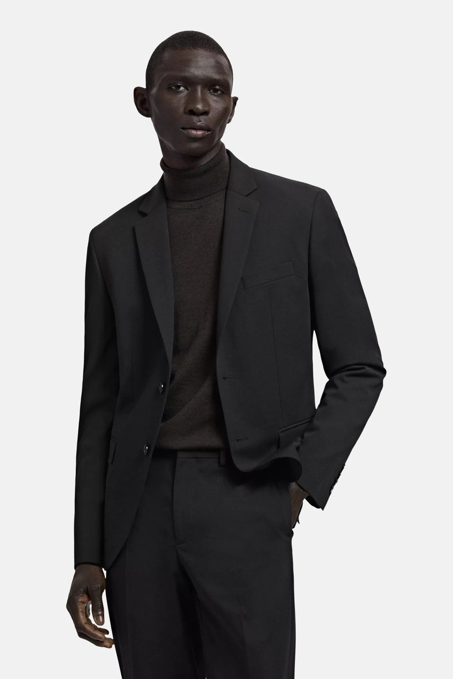 Blazer noire de MANGO, vue de dos sur un mannequin masculin portant un col roulé et un pantalon assorti.
