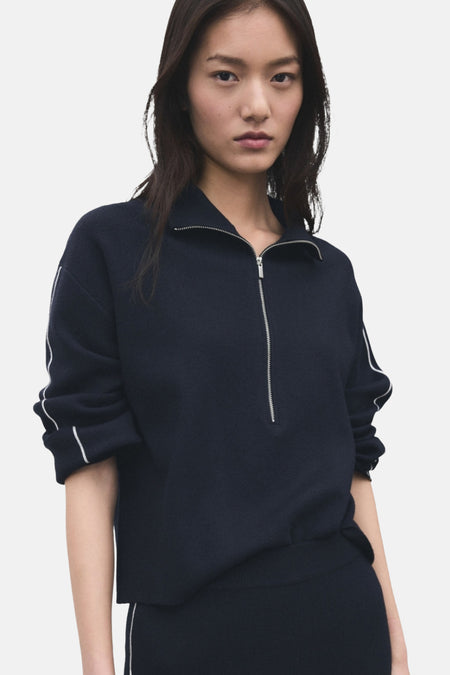 Aziatische vrouw draagt marineblauwe trui met witte strepen.