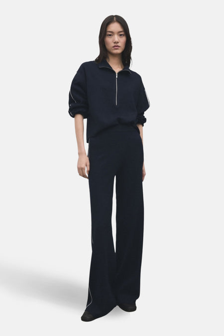 Vrouw in marineblauwe trui en broek met witte strepen.