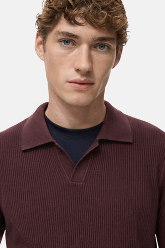 Sweat-shirt bordeaux de MANGO avec col V, en texture côtelée et porté sur un t-shirt bleu marine.