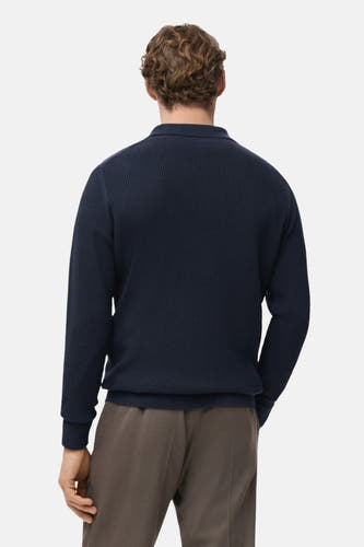 T-shirt bleu à col V de MANGO, dos, avec structure côtelée, associé à un pantalon marron.