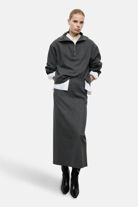 Model draagt grijze trui met lange grijze rok en zwarte laarzen.